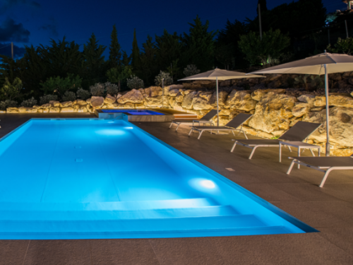 Encontrar inspiração com iluminação ambiente, envolvente rochosa, e uma piscina imaculada com spa. Por: Piscine Design